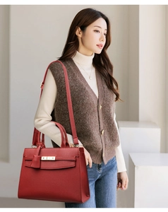 Detail view of red lychee pattern leather handbag with gold metal twist lock and strap