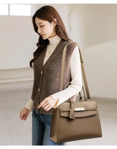 Detail of tan leather tote featuring a gold metal lock and elegant grainy texture