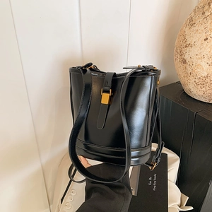 Sac seau noir chic avec fermoir doré et bandoulière pour femme dans un décor studio