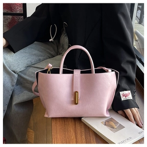 Sac fourre-tout en cuir rose avec fermoir doré sur bureau en bois, style urbain épuré
