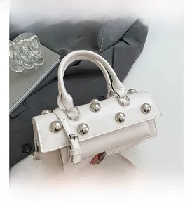 Detail of white glossy handbag featuring oversized silver rivets and elegant top handle