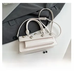 Detailed view of white baguette bag with silver rivets and smartphone size comparison