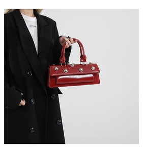 Detail of red glossy leather box bag with silver studs and double top handles