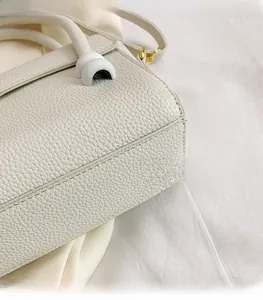 Detailed close-up of white lychee pattern leather texture and premium stitching on handbag