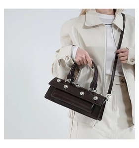Detail of dark brown leather handbag with silver metallic rivet studs on a model