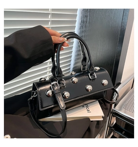 Detail of black glossy handbag with silver metallic studs and punk aesthetic