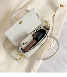 Top view of open white lychee leather handbag showing internal storage and golden clasp