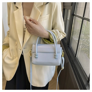 Close-up of light blue handbag with litchi texture and elegant bead clasp closure