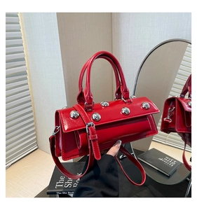 Detail of red patent leather handbag with silver metallic spherical studs and flap closure