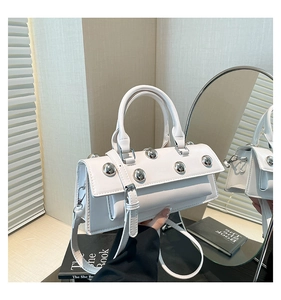 Close-up of white glossy motorcycle bag with metal rivets and adjustable strap