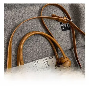 Detail of straw woven bucket bag with knotted brown leather handles and metal hardware