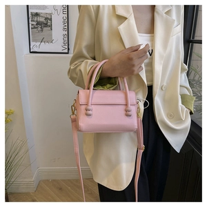 Detailed shot of pink pebble leather handbag with gold accents and top handle