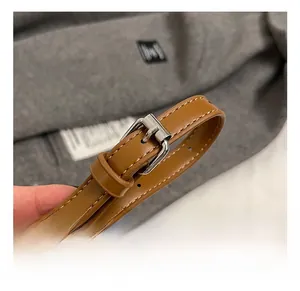 Detail of adjustable brown faux leather strap with silver metal buckle on bucket bag