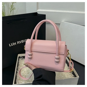Detail view of pink lychee leather handbag with bead accents and removable strap