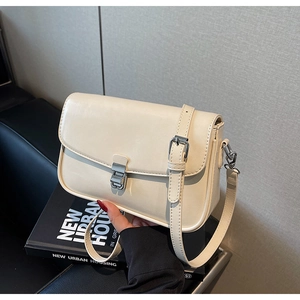 Detail of cream beige crossbody bag featuring silver metal buckle and adjustable strap