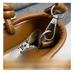 Detailed macro view of silver swivel clasp and zipper on brown pebble leather handbag