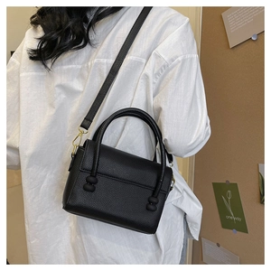 Detail of black pebbled leather texture and black beaded clasp on a stylish handbag