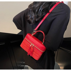 Détail du sac bandoulière rouge avec texture tissée et double fermeture à pompons