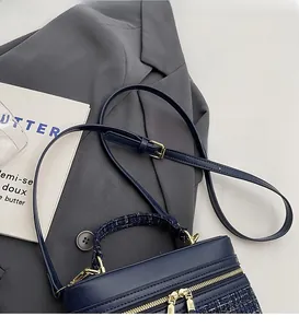 Détail du sac en cuir bleu marine avec poignée en tweed tissé et fermeture dorée