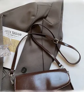 Detail view of smooth brown leather crossbody bag with adjustable strap and metal buckle