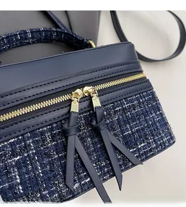 Gros plan des doubles fermetures éclair dorées sur un sac boîte en tweed bleu foncé
