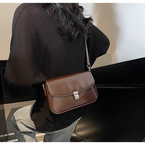Minimalist vintage brown leather crossbody bag shown on a model in a modern interior