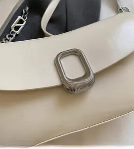 Detail of cream saddle bag featuring polished silver metallic square buckle and V-logo chain