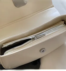 Detail of silver smooth zipper and magnetic closure on beige faux leather bag
