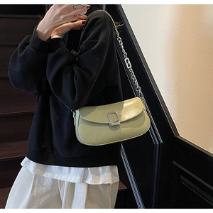 Close-up of sage green faux leather shoulder bag with silver buckle and chain strap