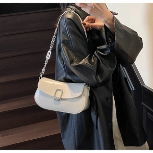 Close-up of a white glossy shoulder bag with silver chain and metal lock on a model