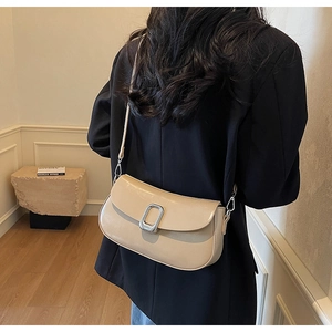 Detail of beige faux leather shoulder bag with silver buckle and adjustable strap