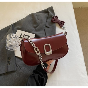 Detail of dark red faux leather shoulder bag with silver square lock and metal chain strap