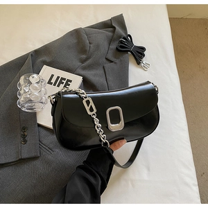 Detailed close-up of a black faux leather baguette bag with silver chain and strap