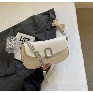 Detail of soft cream faux leather shoulder bag with silver chain on grey blazer