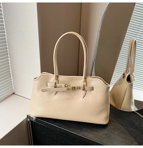 Detail of beige vintage shell bag showing matte leather texture and metal buckle on black wood