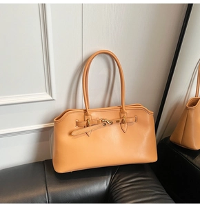Detail of apricot leather shell bag featuring metal buckle and long rounded handles