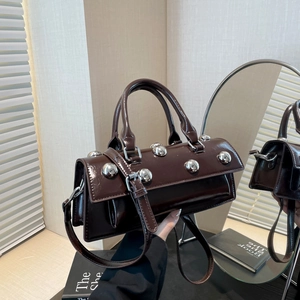 Deep brown patent leather shoulder bag with silver rivet studs in a chic indoor setting