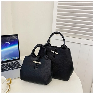 Detail view of black lychee grain leather bucket bags with metal bamboo toggles