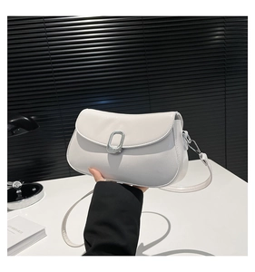 Detailed close-up of white PU leather crossbody bag with lychee texture and silver buckle
