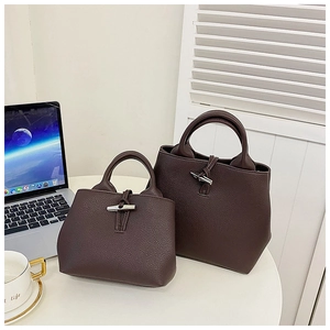 Detail of dark brown lychee grain leather bucket bag with metallic toggle closure