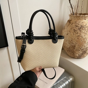Chic beige straw bucket tote with black leather trim and knotted handle detail