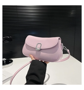 Detail view of a pale pink crossbody bag featuring a silver oval buckle and smooth texture