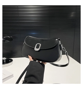 Detail of black smooth leather underarm bag featuring a silver oval metal buckle
