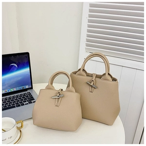 Detail of warm beige lychee grain leather bucket bag with metallic toggle closure