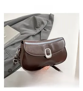 Detailed close-up of dark brown glossy leather shoulder bag with oval silver metal buckle