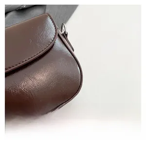 Macro shot of dark brown crinkled glossy leather texture with silver D-ring hardware