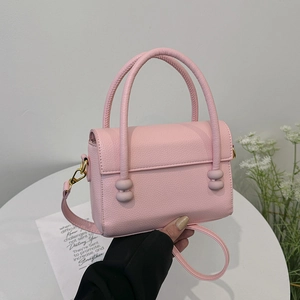 Elegant light pink quilted handbag with dual cylindrical handles and gold hardware