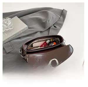 Interior view of chocolate glossy leather shoulder bag showing storage capacity and silver lock
