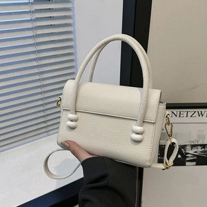 Chic cream white pebble leather handbag with twin white ball accents and shoulder strap