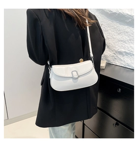 Detail of white semi-oval crossbody bag with silver buckle on a black blazer